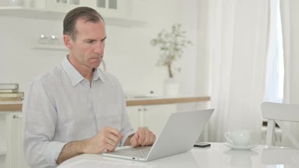 Middle Aged Man Thinking and Working on Laptop at Home