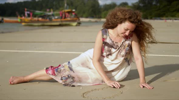 Relaxed Female Drawing on Sand During Beach Walk