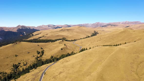 Aerial view of a country road through rural rolling hills and mountain 
