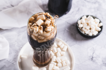 Refreshing fluffy coke with marshmallow in a glass on the table