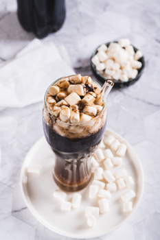 Refreshing fluffy coke with marshmallow in a glass on the table vertical view