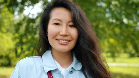 Beautiful Asian Woman Standing Outdoors in Park Smiling Looking at Camera