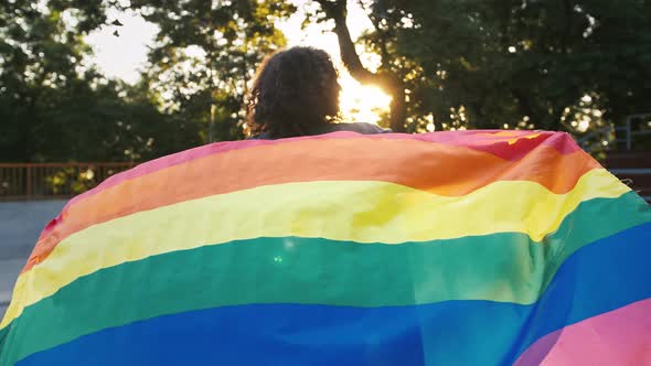 Afroamerican Woman Holding LGBT Pride Flag and Waving It Looking Back and Smiling