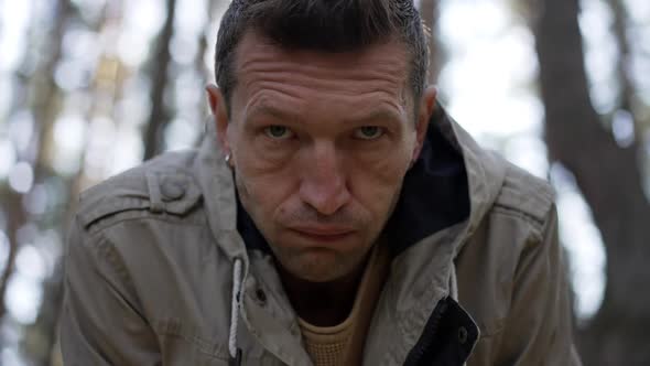 Closeup Portrait of Exhausted Male Survivor Standing in Forest Looking at Camera