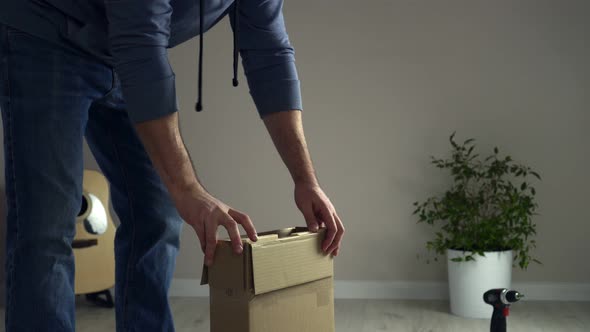 Man Unpacks Cardboard Box Takes Out Pieces of Wooden Furniture