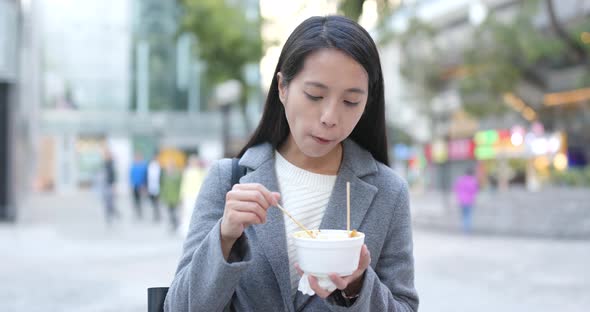 Businesswoman enjoy fish ball at street