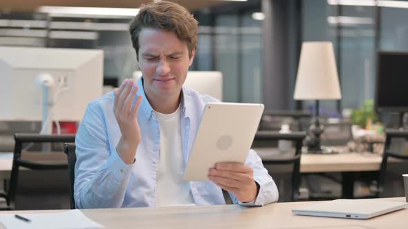 Man Reacting to Loss on Tablet While Sitting in Office