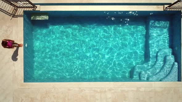 Aerial view of young woman stading next to swimming pool.