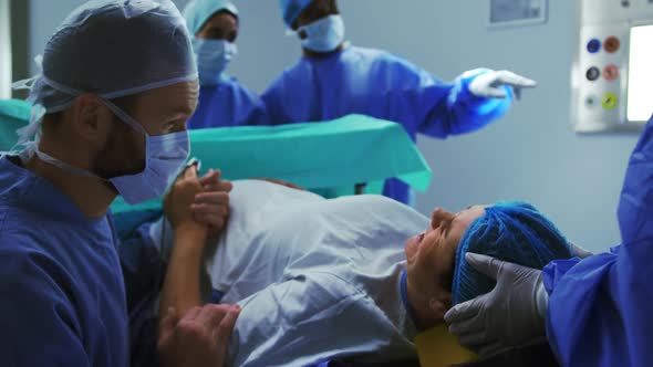Side view of Caucasian man comforting woman during labor pain in operation theater at hospital 