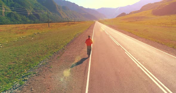 Low Altitude Flight in Front of Sporty Man at Perfect Asphalt Road