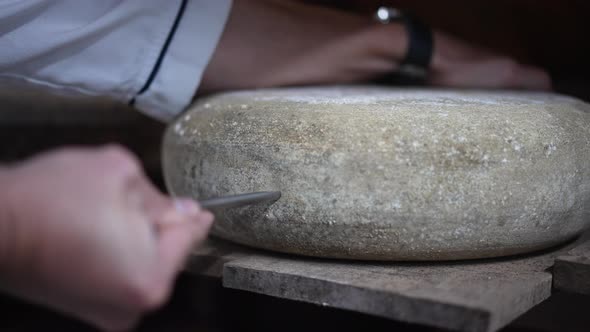 Male Caucasian Hand Inserting Cheese Trier in Cheese Wheel Turning Tool in Slow Motion