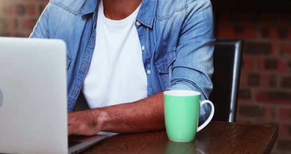 Man having coffee while working on laptop