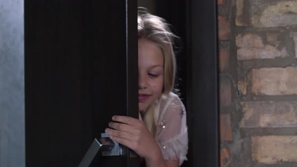 Adorable Blonde Girl Peeping Through Crack in Door