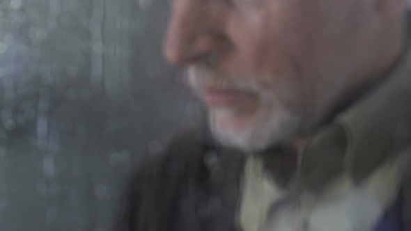Mature Lonely Man Sighing Heavily Standing Near Rainy Window and Looking Outside