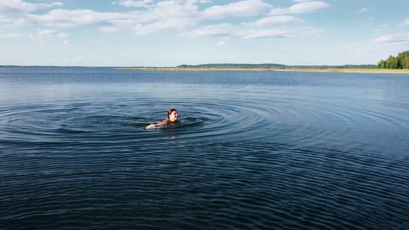 Young Sexy Woman In Red Swimsuit Swimming On Surface Of Water In Lake At Summer