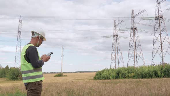 An Electrical Engineer Forcing a Drone To Inspect High Voltage Poles Before Starting a Project