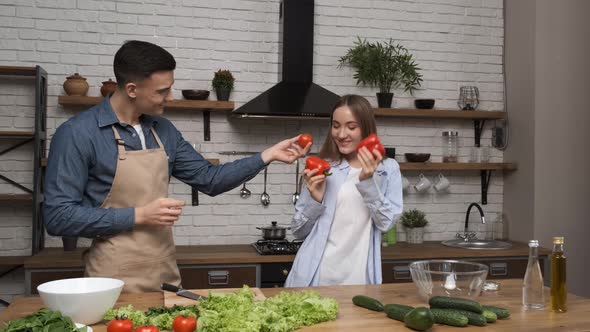 Cooking Salad at Home Young Woman and Man Having Fun and Dancing in Modern Kitchen