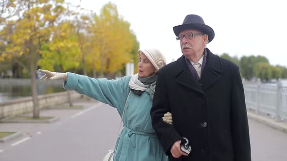 Concept of old age, retirement and people - happy senior couple walking in autumn city park.