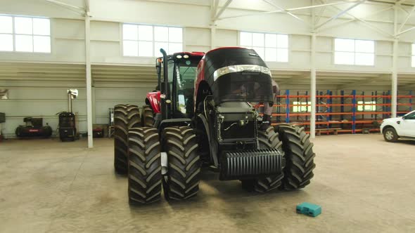 Aerial View on a Man Repairing a Modern Tractor in a Garage