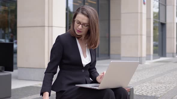 Woman in Suit Working with Laptop on Street