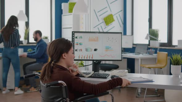 Disabled Businesswoman Discussing with Coworker at Phone