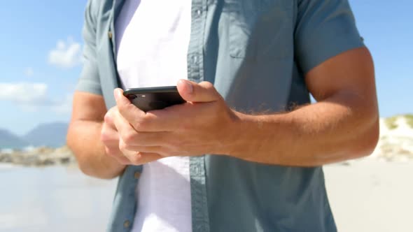 Mid section of man using mobile phone at beach on a sunny day 4k