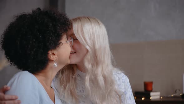 Lesbian Couple Kissing and Smiling Sitting on the Couch