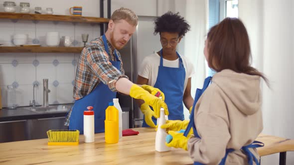 Group of Diverse Young Janitors in Uniform Cleaning Kitchen at Home