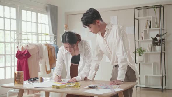 Two Young Asian Fashion Designers Sketching At Fashion Design Studio