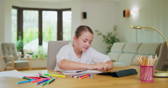 Focused Teen Girl at the Desk Scrolls Tablet Then Stretches and Yawns with Closed Eyes Felttip Pens