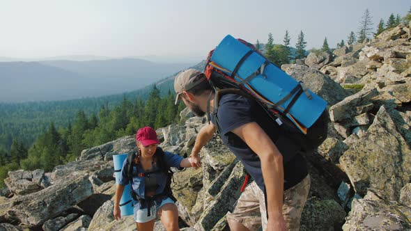 Man Giving Hand Woman to Help Her to Climb the Mountain and Reach the Top