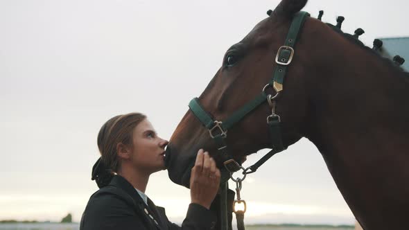 Female Horse Owner Holding Bridle Of Her Horse And Kissing Her Horse With Love