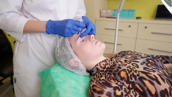 Professional Cosmetologist Doing Xeomin Injections for Young Woman Visiting Beauty Salon