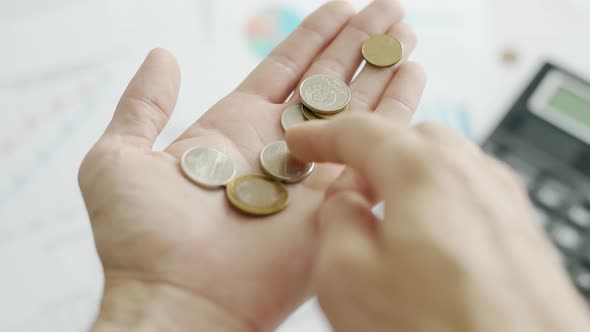 A Man Hands are Calculating Expenses for a Month on Background of Calculator and Graphs