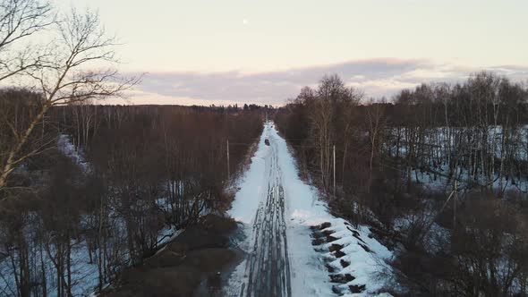 Snowy Winter Landscape with a Road in the Forest at Sunset Aerial View