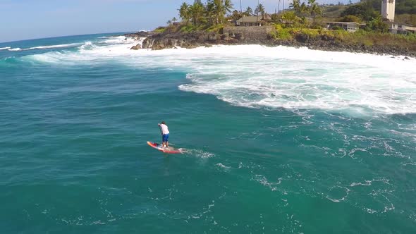 Aerial view of a man sup stand-up paddleboard surfing in Waimea, Hawaii