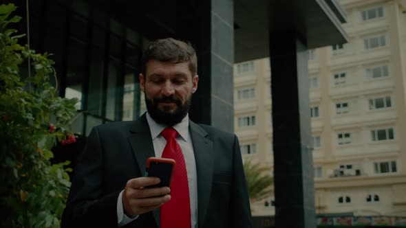 A Business Man Texting Phone in the Street