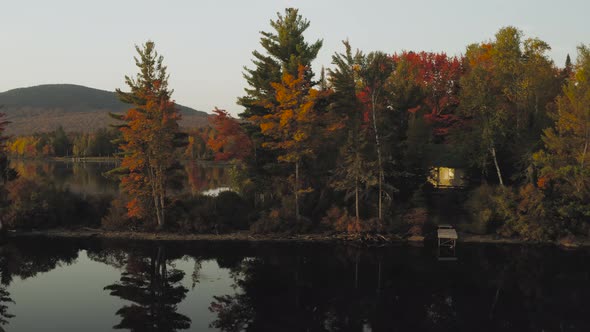 Autumn reflections on a calm lake at sunrise AERIAL SLIDE