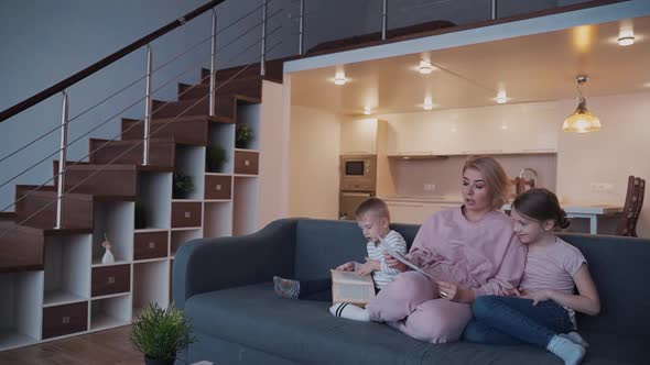 Woman Hold Daughter Draw in Hands While Her Son Play with Book