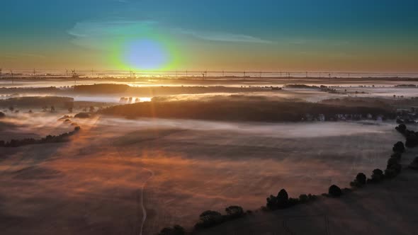 Misty sunrise over fields and wind farms