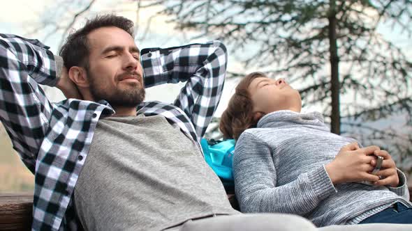 Dad and his teenage son with closed eyes relaxing outdoors