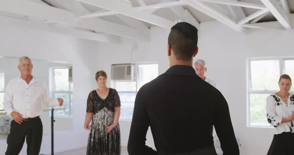 mixed race male dance teacher taking a ballroom dancing class at a dance studio