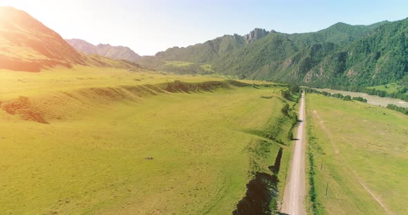 Aerial Rural Mountain Road and Meadow at Sunny Summer Morning. Asphalt Highway and River.