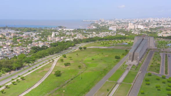 Aerial forward over park around Faro Colon and city in background, Santo Domingo