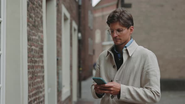 Man Looking at Camera While Standing on Street with Mobile