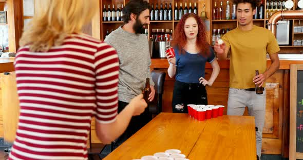 Friends playing beer pong on table in bar 4k