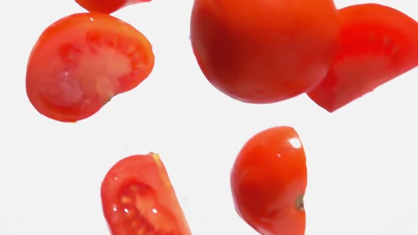 Fresh Ripe Tomato Halves are Falling Down Diagonally on the White Background