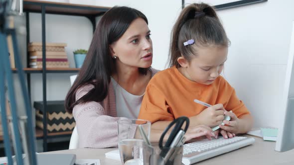 Cute Little Girl Kissing Mother While Woman Working with Computer From Home