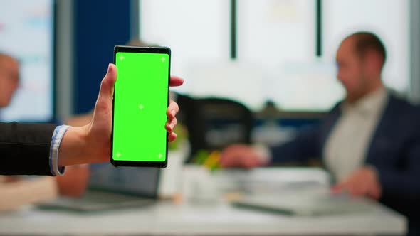 Businesswoman Holding Smartphone with Green Screen During Conference