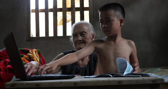Boy Studying And Using Computer With His Grandmother